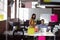 Caucasian male and female colleague in discussion at desk looking at laptop and drinking coffee