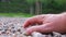 Caucasian Male Grabbing Small Pebble Rocks from Ground With Bare Hand