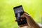 Caucasian male hand dialing his Mom on his cell phone. Close up shot, shallow depth of field, green defocused background