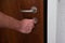 Caucasian male hand unlocking apartment brown wooden door from inside close up shot
