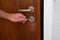 Caucasian male hand unlocking apartment brown wooden door from inside close up shot