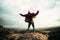 Caucasian male hiker standing on top of mountain with open arms successfully reaching mountain peak