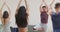 Caucasian male instructor demonstrating yoga poses to diverse group at yoga class