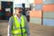 Caucasian male manager in white hard hat helmet and high-visibility vest walking in Container Terminal