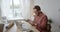 Caucasian male student excited to finish project sitting at indoor workspace by laptop