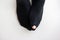 Caucasian male toe sticking out of worn out short nylon black plain socks with hole top view