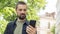 Caucasian man with a beard holds a phone on his outstretched hand and takes a selfie. The blogger communicates by video call. The