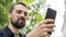 Caucasian man with a beard holds a phone on his outstretched hand and takes a selfie. The blogger communicates by video call. The