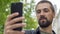 Caucasian man with a beard holds a phone on his outstretched hand and takes a selfie. The blogger communicates by video call. The