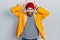 Caucasian man with beard wearing yellow raincoat posing funny and crazy with fingers on head as bunny ears, smiling cheerful