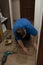 Caucasian man in a blue t-shirt sets up floor plastic skirtings. Close-up on a plastic floor connector plastic baseboard