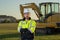 Caucasian man, construction worker in helmet at construction site. Industry engineer worker in hardhat near bulldozer or