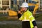 Caucasian man, construction worker in helmet at construction site. Industry engineer worker in hardhat near bulldozer or