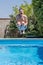 Caucasian man with a funny expression takes a cannonball bomb dive in the swimming pool on a sunny day
