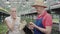 Caucasian man giving organic apple to young pretty woman in greenhouse. Portrait of positive colleagues eating fruits in