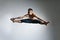 Caucasian man gymnastic leap posture on grey