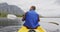 Caucasian man having a good time on a trip to the mountains, kayaking on a lake, holding a paddle