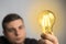 Caucasian man holding glowing incandescent light bulb