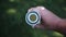 A caucasian man holds a white bottle and looks through a round hole inside