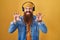 Caucasian man with long beard listening to music using headphones smiling funny doing claw gesture as cat, aggressive and sexy