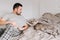 Caucasian man playing with a cat. Angry furious cat attacking scratching owner master. Guy lying on bed at home with oriental cat