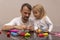 Caucasian man plays with his daughter making colorful animals from playdough