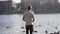 Caucasian man with ponytail feeds lake birds in Copenhagen