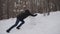 Caucasian man rolls large snow globe with effort. He slips, falls, gets up.