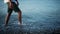 Caucasian man in shorts walks slowly in shallow water of pebble beach.