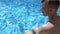 Caucasian man sitting on the pool bar with clear azure water. Adult male relaxing by the swimming pool. Summer vacation concept. C