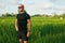 Caucasian Man Standing On Rice Field In Morning. Sporty Male In Sportswear Resting After Workout.