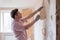 Caucasian man tearing off old wallpaper from wall preparing for home redecoration