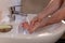 Caucasian man thoroughly washing hands in wash basin under water tap. Personal hygiene as coronavirus COVID-19 pandemic spread