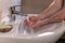Caucasian man thoroughly washing hands in wash basin under water tap. Personal hygiene as coronavirus COVID-19 pandemic spread