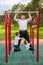 Caucasian man and two boys doing exercises outdoors. The father pulls himself up on the horizontal bar with his sons on