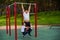 Caucasian man and two boys doing exercises outdoors. The father pulls himself up on the horizontal bar with his sons on