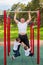 Caucasian man and two boys doing exercises outdoors. The father pulls himself up on the horizontal bar with his sons on