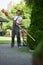 Caucasian man in uniform shaping hedge with electric trimmer