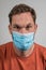 Caucasian man is wearing or presenting a flu or covid face mask or protective mask over his mouth. Coronavirus prevention man,