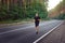 Caucasian middle age man athlete runs sunny summer day on asphalt road in the forest