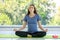 Caucasian millennial young happy female prenatal pregnant mother in casual outfit sitting crossed legs on yoga mat smiling closed