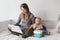 Caucasian mother with baby working online from home on Internet. Workplace of freelancer woman with kid. Coronavirus self-