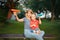 Caucasian mother and boy toddler son sitting together outdoor on summer sunset playing with colored paper air planes.