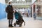 Caucasian mother with her little daughter sitting in children carriage walking in a shopping mall, adult woman wearing face mask