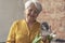 caucasian older retired woman holding bunch of white flowers and a black and white portrait from her past