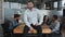 Caucasian pensive young male leader sitting on table in conference room confident boss smiling looking at camera