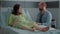 Caucasian person with pregnancy sitting with man in hospital ward