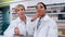 caucasian pharmacist assisting female intern using digital tablet pointing to medicines on the shelves