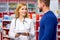 Caucasian pharmacist is working with customer in modern drugstore