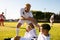 Caucasian player giving hand to injured teammate lying on field in getting up against clear sky